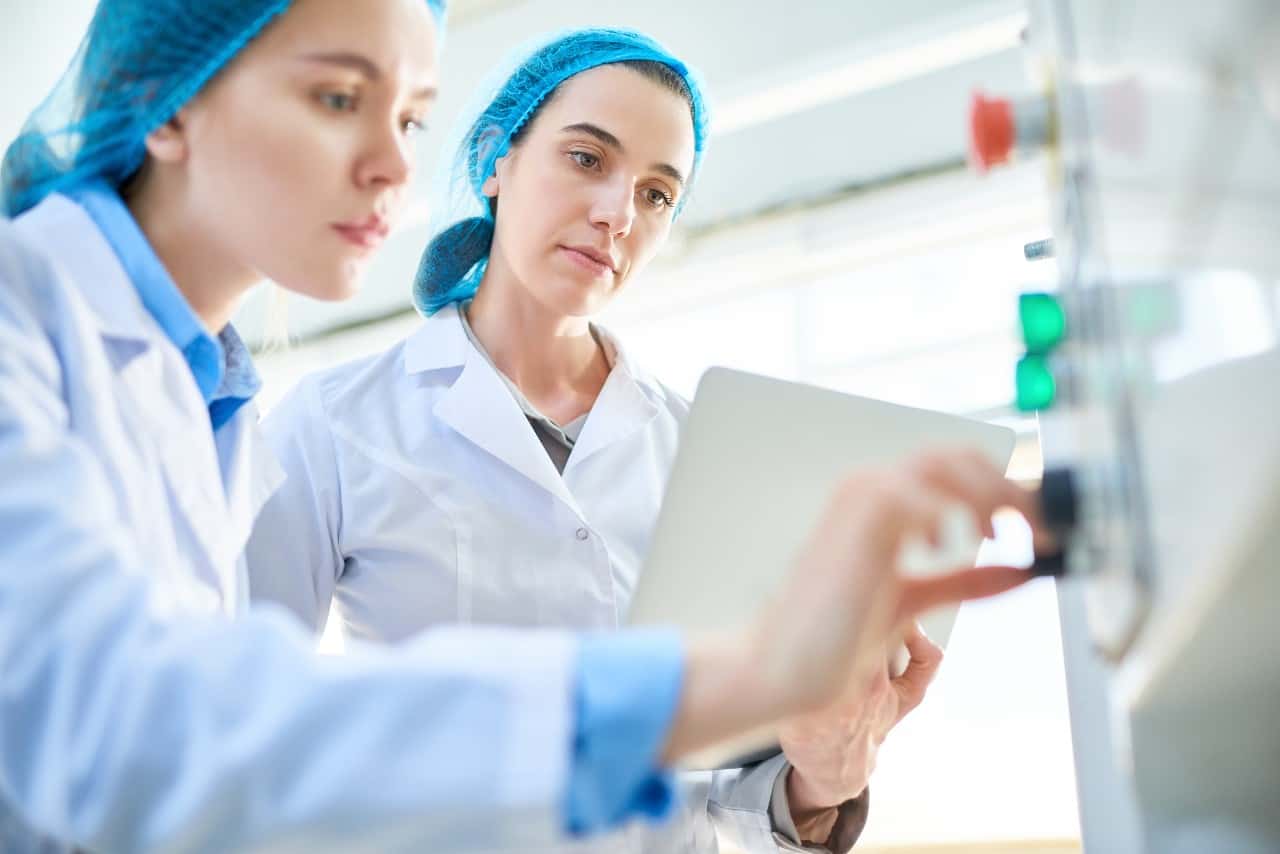 Two female scientist operating a machine