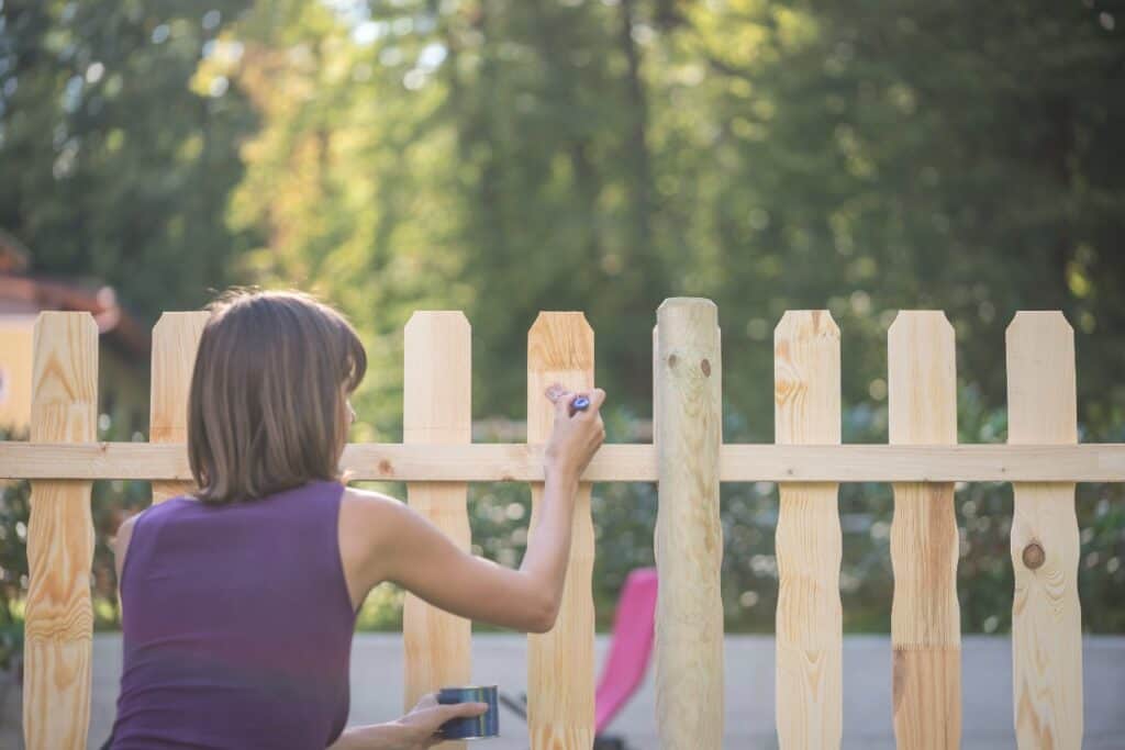 Woman coating a wooden fence